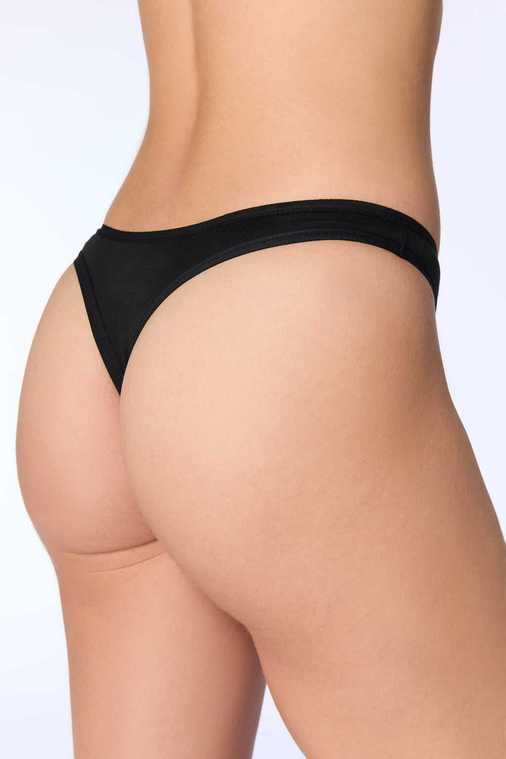 Women's organic cotton thong in black, back three-quarter view on model