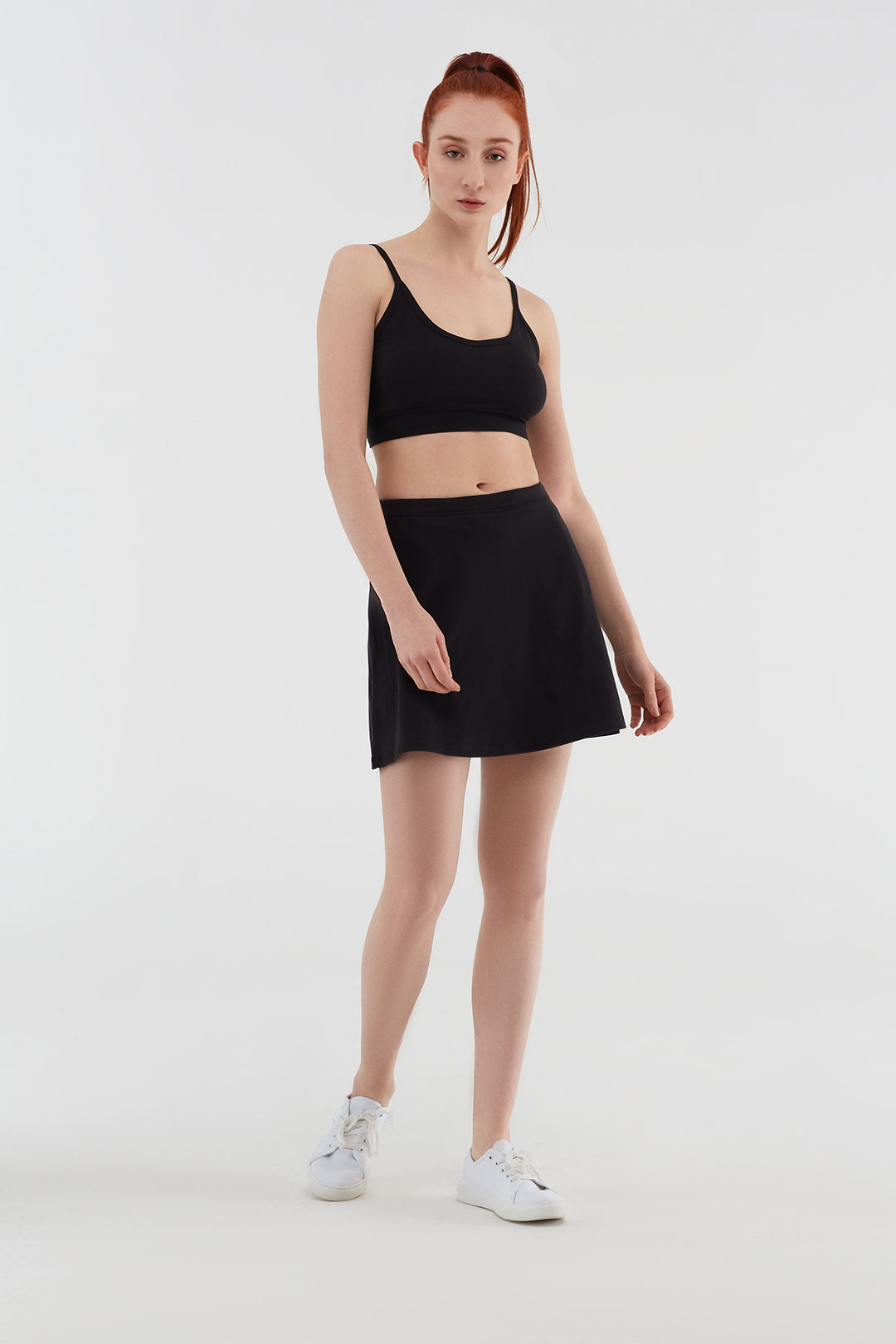 Women's organic cotton bralette in black, full-length view on model, styled with a skirt