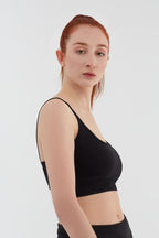 Women's organic cotton bralette in black, side view on model