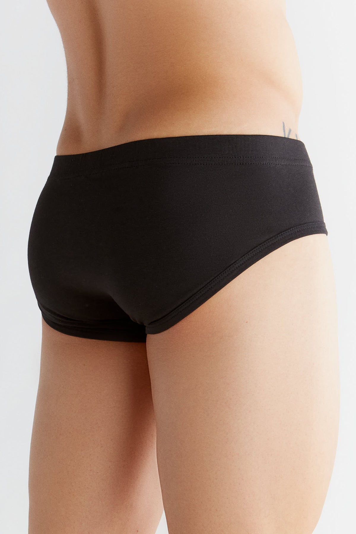 Men's organic cotton briefs in black, back three-quarter view on model