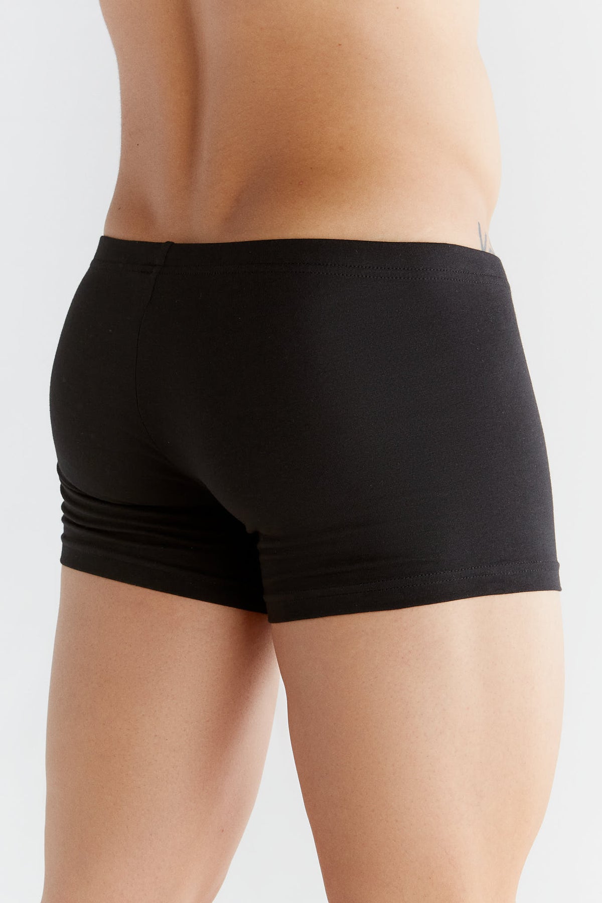 Men's organic cotton boxer briefs in black, back three-quarter view on model